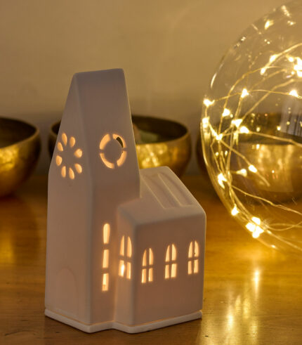 Photophore en porcelaine blanche représentant une église de village. Il diffuse une lumière douce et donne une touche de poésie à votre intérieur. Parfait pour votre décoration des fêtes de fin d’année.